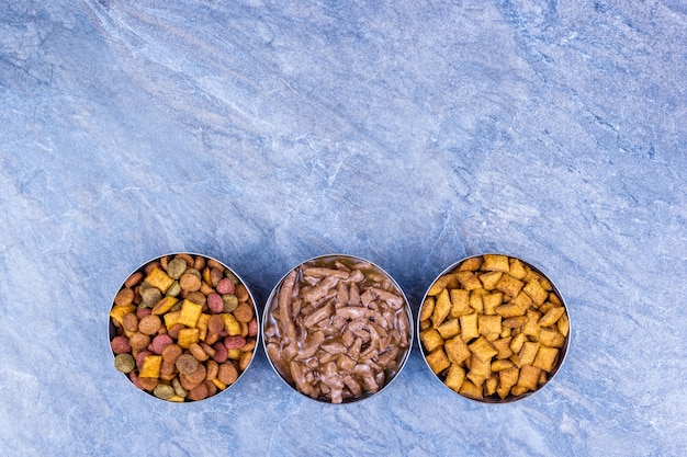 A close-up shot of different types of dog food: dry kibble, wet food, and dental chews. The focus is on the texture and composition of each food type, highlighting their potential impact on dental health.