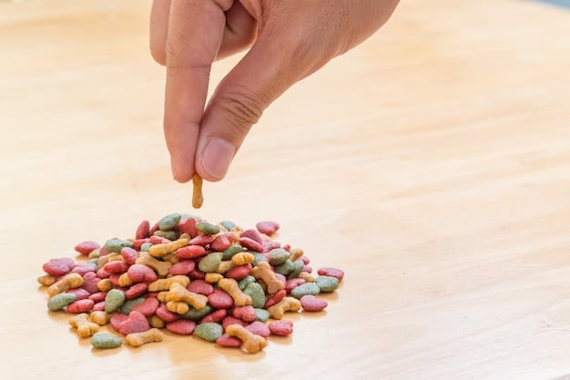 A close-up shot of a clicker in a person's hand, with various cat treats scattered around it on a wooden table.