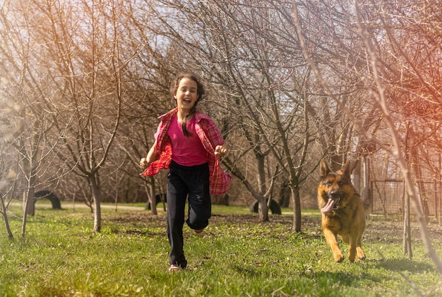 A happy, active dog running in a park with its owner in the background on a sunny day, demonstrating the importance of regular physical activity for canine health.