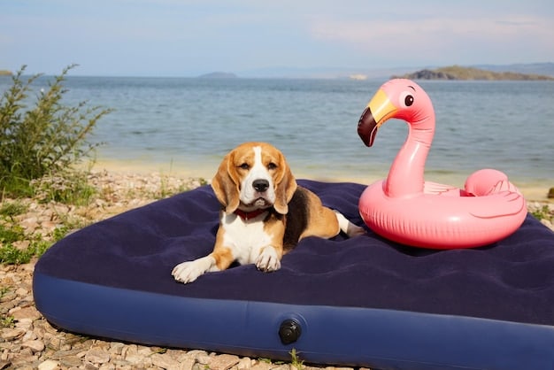 A beagle lying comfortably under a large beach umbrella on a sunny beach. The dog is in the shade, looking relaxed, with sand and water visible in the background.