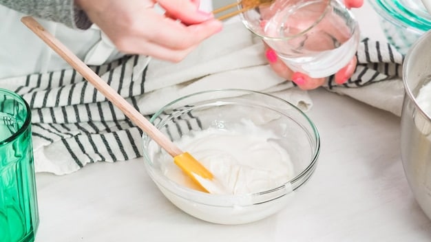 A person preparing a DIY pet stain remover solution, mixing baking soda and vinegar in a bowl. The ingredients are clearly visible and well-lit.